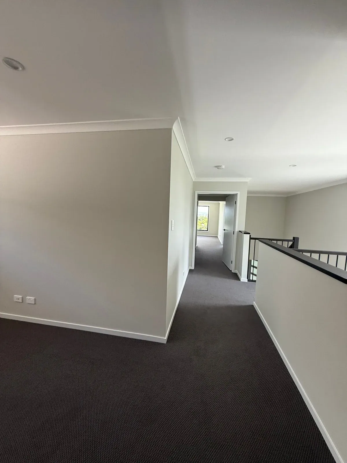 An upstairs hallway in Oxley, Brisbane, with freshly painted walls, ceiling and cornices beside a black balustrade